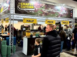 A busy exhibition display with signs displaying prices and various products.