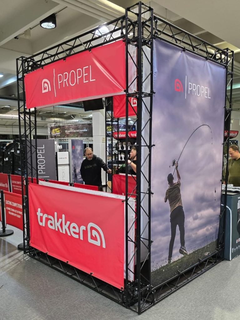 Trade show display for Trakker featuring a fisherman casting a line against a scenic background.